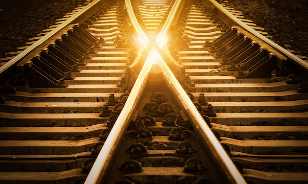 Railroad tracks converging in an X shape with golden light